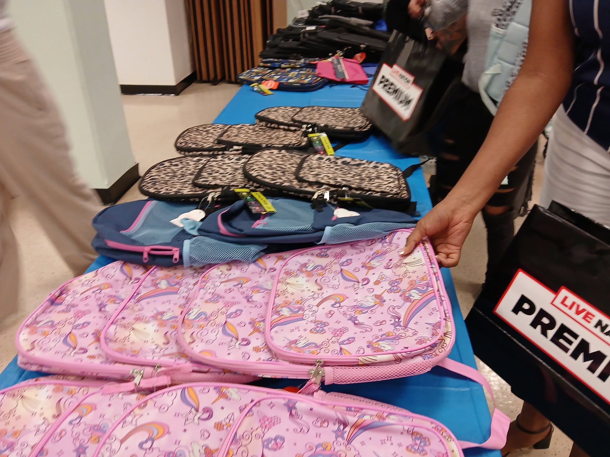 Woman reaches for a bright pink backpack in St. Ann's Center's auditorium.